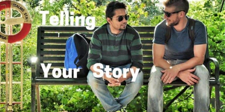 Two young men sitting on a park bench talking to each other